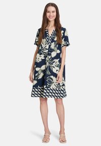 Námořnické květinové šaty s krátkými rukávy, s výstřihem do V, světle zeleným květinovým vzorem a zvlněným lemováním. Lehká látka.