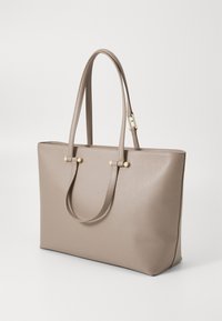 Beige leather tote bag with textured finish, dual handles, and brass hardware accents. Features a spacious rectangular shape.