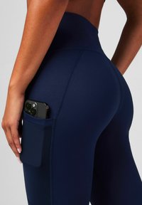 Marineblaue High-Waist-Leggings aus stretchbarem Stoff, mit einer Seitentasche für ein Smartphone und flachen Nähten für zusätzlichen Komfort.