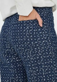 Pantalons en sequins bleu marine avec une finition en denim texturé, dotés d'une poche latérale et d'une coupe ajustée.