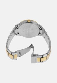 Uračni jekleni ročni ura z dvobarvnim zapestnicam iz srebra in zlata, kvadratno sponko in gravirano hrbtno stranjo ohišja, ki prikazuje ime blagovne znamke.