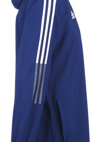 Marinefarbene Sportjacke mit weißem Drei-Streifen-Design auf den Ärmeln, ausgestattet mit einer glatten Textur und seitlichen Reißverschlusstaschen.