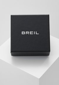 Caja cuadrada de cartón negro con textura mate. En la parte frontal presenta el texto blanco "BREIL" en una tipografía moderna.