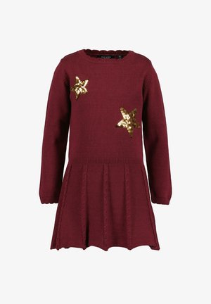 Robe en maille bordeaux à manches longues avec jupe plissée et deux patchs étoiles en sequins dorés sur la poitrine.