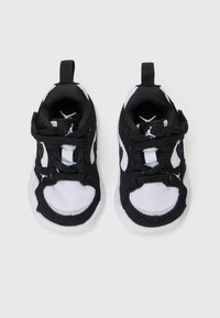 Chaussures de sport en noir et blanc avec une tige en maille, semelle en caoutchouc, lacets noirs et tirette, arborant le logo Jordan sur les côtés.