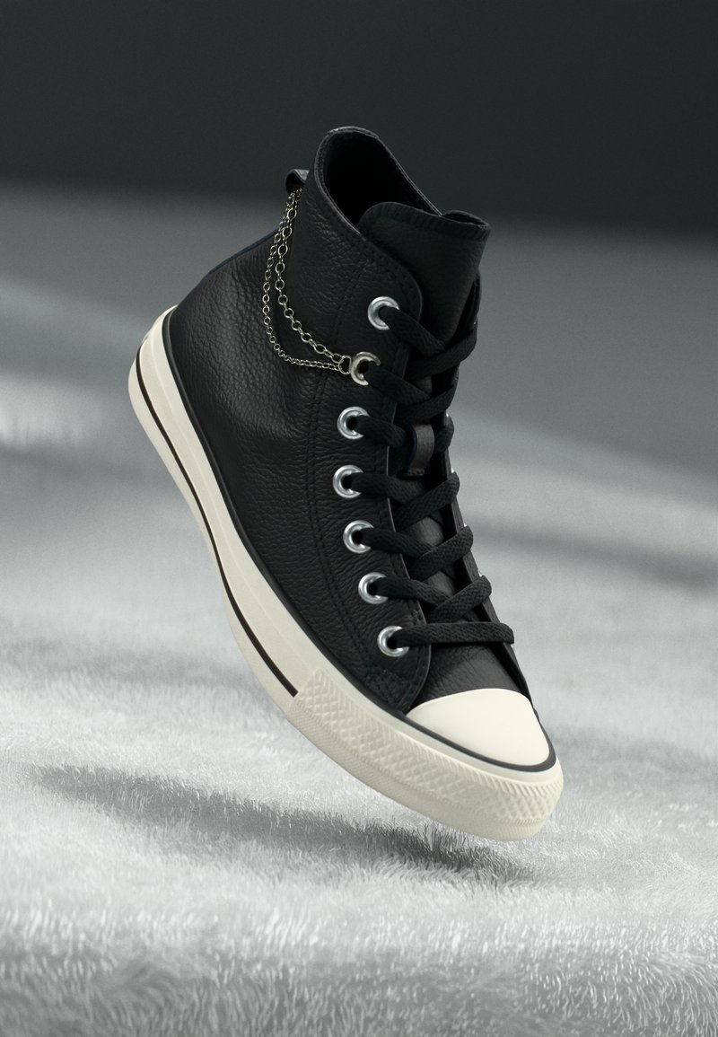 Sneaker high-top nera realizzata in pelle texturizzata, con punta in gomma bianca, occhielli argentati e un accento decorativo a catena.