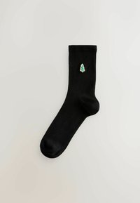Schwarze Socke aus glattem Baumwollmaterial, mit einem kleinen gestickten grünen Weihnachtsbaum an der Seite. Klassisches Crew-Längen-Design.