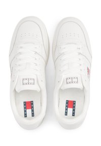 Baskets basses blanches en cuir. Caractéristiques incluent un bout perforé, des lacets plats et un logo rouge, blanc et bleu sur la languette.
