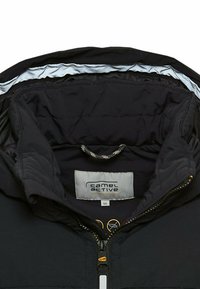 Schwarze isolierte Jacke mit hohem Kragen, ausgestattet mit einem Frontreißverschluss, einem Markenlabel und einer Innenschlaufe zum Aufhängen. Glatte Textur, matte Oberfläche.
