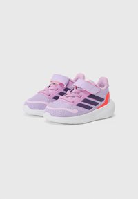 Baskets de sport violettes avec tige en mesh, deux bandes Velcro, rayures violettes foncées contrastantes et semelle en caoutchouc blanc avec accents orange.