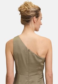 Jedno-ramienna, oliwkowa sukienka z satyny o gładkiej teksturze. Posiada dyskretny zamek z tyłu i dopasowaną sylwetkę.