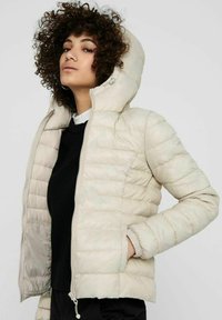 Puffy beige jakke med hette, ribbede mansjetter og vertikal søm. Lett materiale, glidelås foran og sidelommer.