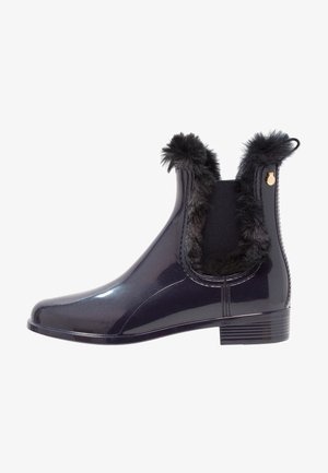 Zwarte glanzende enkelboots met nep bont trim en elastische zijkanten. Heeft een lage hak en een subtiele metalen accent aan de achterkant.