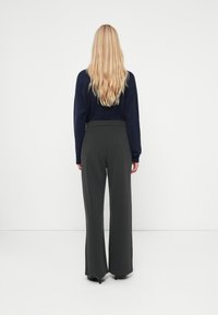 Dark green, wide-leg pants with vertical pinstripes, high waist, and soft fabric. Paired with a navy long-sleeve top.