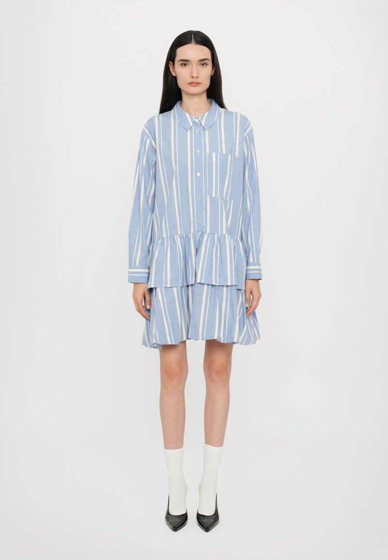 Blau-weiß gestreiftes Hemdkleid mit kragenförmigem Ausschnitt, Knopfleiste und gestuften Rüschensaum. Lange Ärmel und seitliche Taschen.