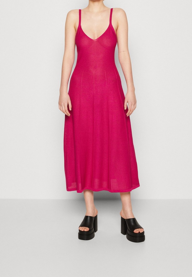 Fuchsia utan ärm midi-klänning med V-ringning, åtsittande bodice och utsvängd kjol. Bärs med stora svarta platåsandaler.