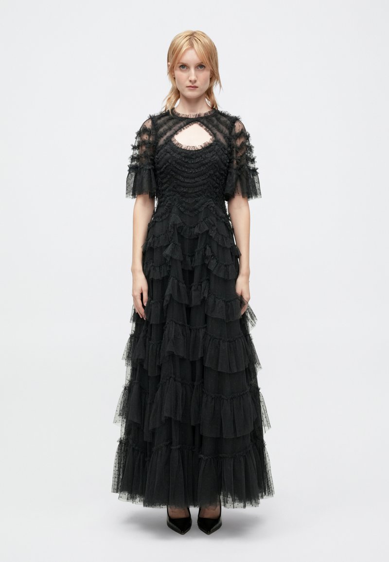 Czarna, warstwowa maxi sukienka z tiulu z falbaniastymi akcentami, przezroczystymi krótkimi rękawami i dekoltem w kształcie łezki. Wykończona dopasowanym gorsetem.