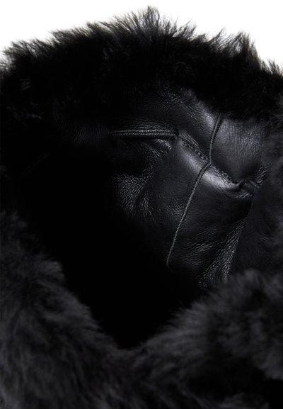 Interni in pelle nera con morbido bordo in pelliccia nera. Caratterizzato da una superficie liscia e dettagli di cucitura visibili. Progettato per calore e comfort.