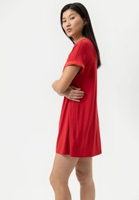 Abito rosso a maniche corte realizzato in un tessuto morbido e leggero, con una vestibilità rilassata e scollatura a girocollo, caratterizzato da una superficie liscia e privo di motivi.