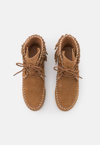 Hnědé sukně kotníkové boty z broušené kůže s fringingovými detaily, bílým šitím a kulatou špičkou. Mají šněrování a polstrovaný límec.