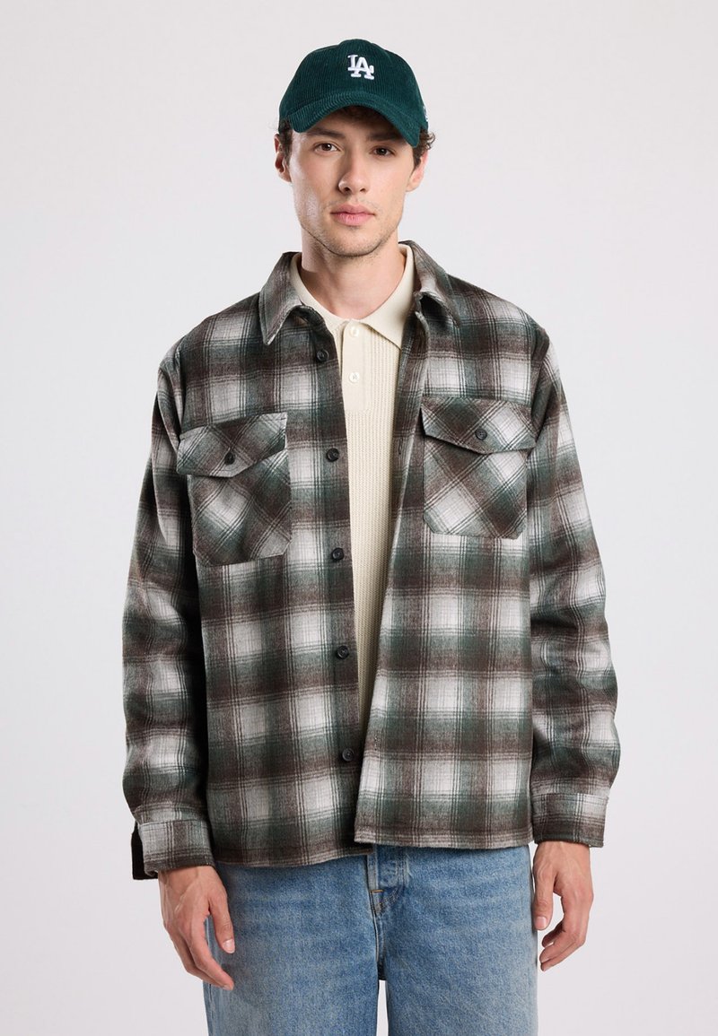 Geruite flanellen shirt in groene, bruine en witte tinten, met een knoopsluiting aan de voorkant, twee borstzakken en een relaxte pasvorm. Draag het over een beige trui.