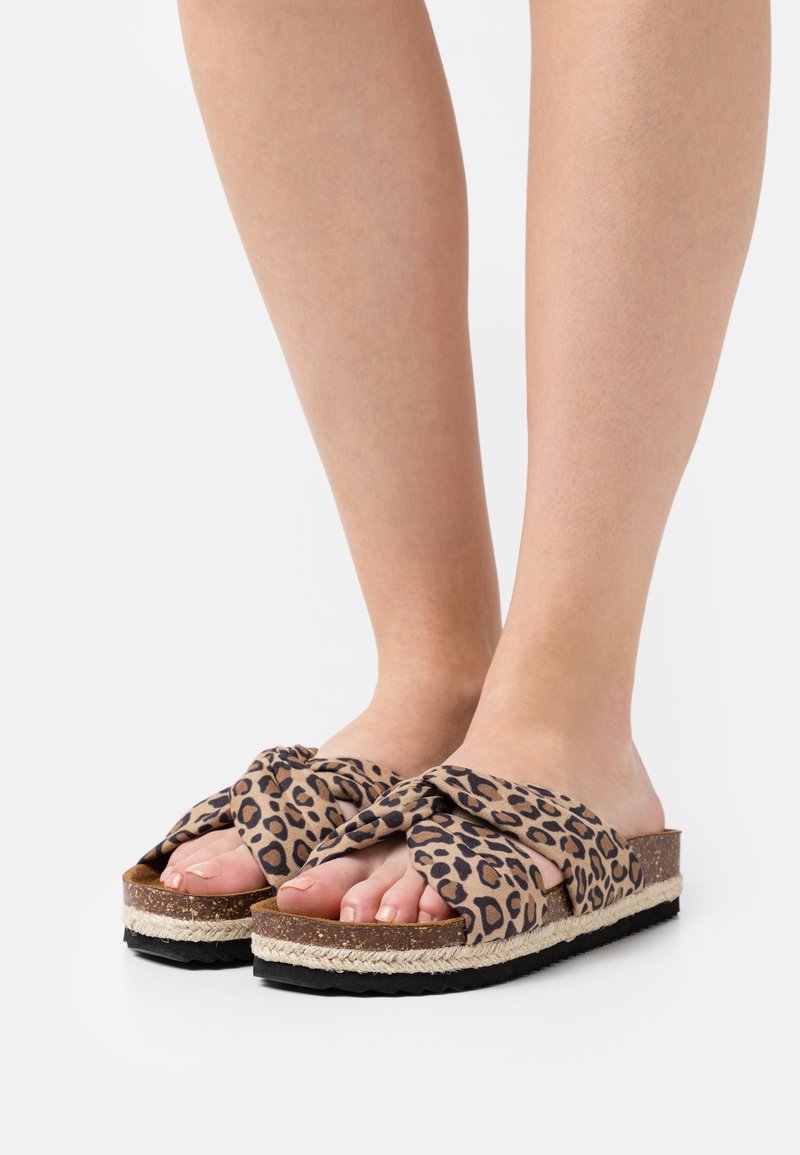 Sandales à imprimé léopard avec un dessus en tissu tordu, semelle en jute tissée plate et semelle extérieure en caoutchouc noir contrastant. Design décontracté et à bout ouvert.