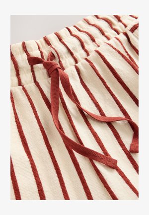 Kreemikas triibuliste kangastega lühikesed püksid, punaste vertikaalsete triipudega. Omavad elastset vöökohaga ja lipsuga kokkuseadmist. Pehme tekstuur.