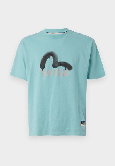 Ljusblå bomull T-shirt med en svart och grå spraymålad logotyp. Korta ärmar, rundad hals och ett litet varumärkesetikett vid fållen.