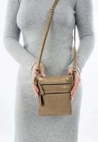 Borsa a tracolla metallica oro con molteplici scomparti con zip. Texture liscia, tracolla regolabile e branding discreto sulla parte frontale.