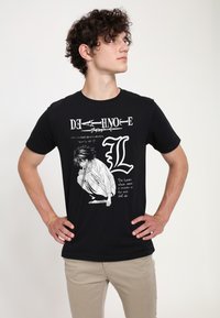 Camiseta de algodón negra con un diseño gráfico de un personaje de Death Note, con texto blanco e ilustración en blanco y negro.
