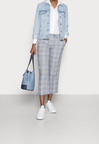 Jeansjacka, vit skjorta, grå rutiga cropped-byxor, vita sneakers och en blå bucket bag med marinblå accenter. Har varierande texturer och mönster.