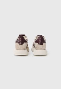 Baskets en cuir et daim beige et bordeaux, avec une semelle plate, un talon rembourré et une languette pour un enfilage facile.
