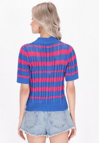 Krótki sweter z dzianiny w kolorze niebieskim, z różowymi i czarnymi wzorami w kratę, z ribb chowandą pod szyją i na dole. Otwarta struktura dodaje wizualnego zainteresowania.