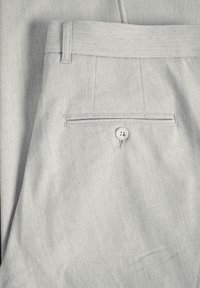 Jasnoszare spodnie z teksturowanej tkaniny, z tylną kieszenią i guzikami. Prosty fason, dopasowany krój, bez widocznych wzorów.