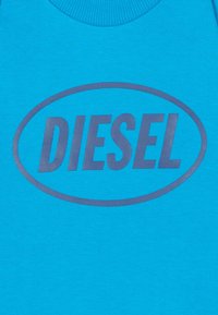Felpa turchese con logo grafico rotondo in grigio scuro con la scritta "DIESEL", presenta un collo a coste e una texture liscia in cotone.