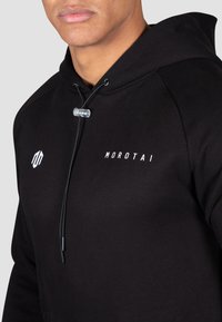 Hanorac negru cu capuciu, confecționat din bumbac moale, având un logo alb, închidere cu șnur și manșete ribbate.