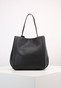 Černá kožená taška přes rameno se prostorným, strukturovaným tvarem, hladkým povrchem a dlouhými uchy, minimalistický design bez viditelného kování.