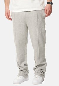 Graue Baumwoll-Sweatpants mit elastischem Bund und Seitentaschen, in einem lockeren Schnitt und mit Bündchen am Saum, kombiniert mit weißen Sneakers.