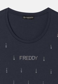 Camiseta azul marino hecha de una tela suave con cuello redondo, que presenta acentos de strass y la palabra "FREDDY" en letras brillantes.