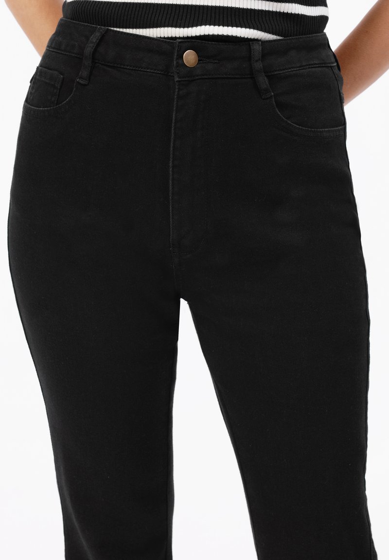 Czarne jeansy z wysokim stanem wykonane z denimu, posiadające pięć kieszeni, zapięcie na mosiężny guzik oraz gładką fakturę bez widocznych wzorów.