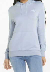 Sudadera con capucha de color azul claro con bolsillo tipo canguro, puños y dobladillo acanalados, con el logo blanco de Puma en el pecho. Textura de tela suave.