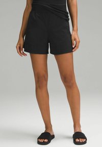 Schwarze Sportshorts mit entspannter Passform, ausgestattet mit einem elastischen Bund und seitlichen Taschen. Glatter Stoff, Länge bis über das Knie.