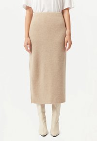 Beige ribbat stickad midikjol med hög midja. Tyget har en mjuk textur. Matchas med knähöga krämfärgade stövlar.