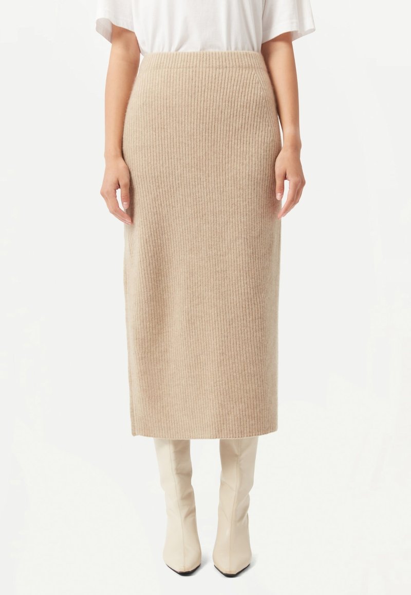 Beige ribbat stickad midikjol med hög midja. Tyget har en mjuk textur. Matchas med knähöga krämfärgade stövlar.