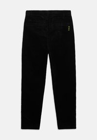 Zwarte corduroy broek met twee achterzakken en een klein neon groen driedubbel stiksel detail op het rechter zakgebied.