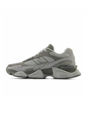 Grå New Balance sportssko med mesh- og ruskinddetaljer, tyk struktureret sål og snørebånd, vist fra siden på en hvid baggrund.