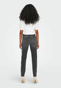 Jeans de tiro alto y pierna recta en mezclilla gris oscuro, con bolsillos traseros, trabillas y dobladillos doblados, combinados con una camiseta blanca.