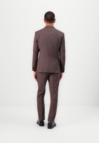 Abito da uomo in tessuto bordeaux scuro. Giacca su misura con taglio dritto, pantaloni abbinati e scarpe nere. Design pulito e moderno senza motivi.