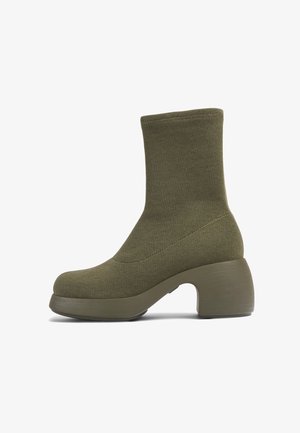 Botte chaussette mi-mollet vert olive avec tige en tissu tricoté et talon bloc épais, sur fond blanc.