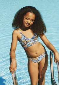 Maillot de bain deux pièces avec un motif de feuilles de palmier vibrant en bleu, orange et jaune. Le haut a des bretelles fines et un décolleté arrondi.